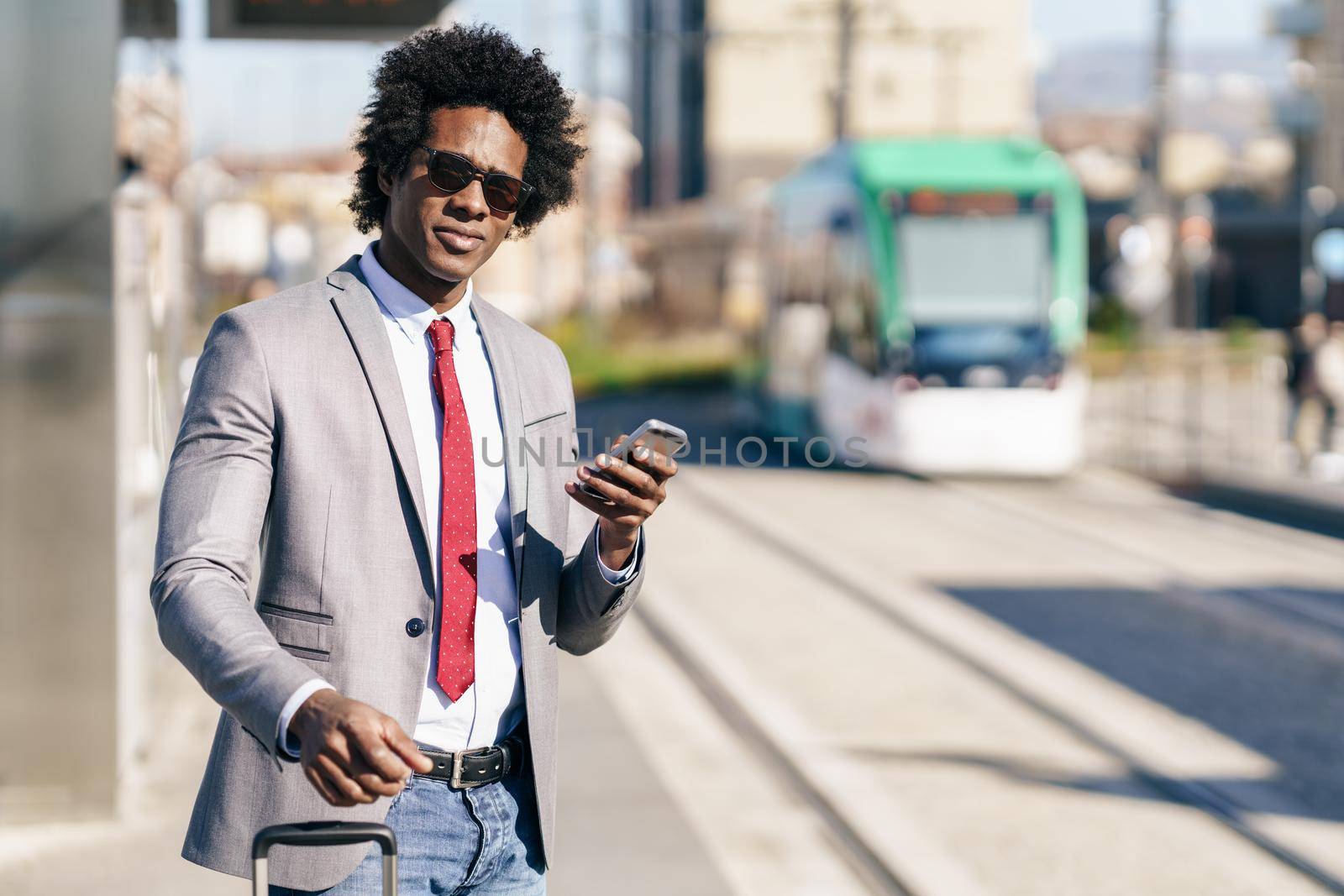 Black Businessman waiting for the next train. Man with afro hair commuting.