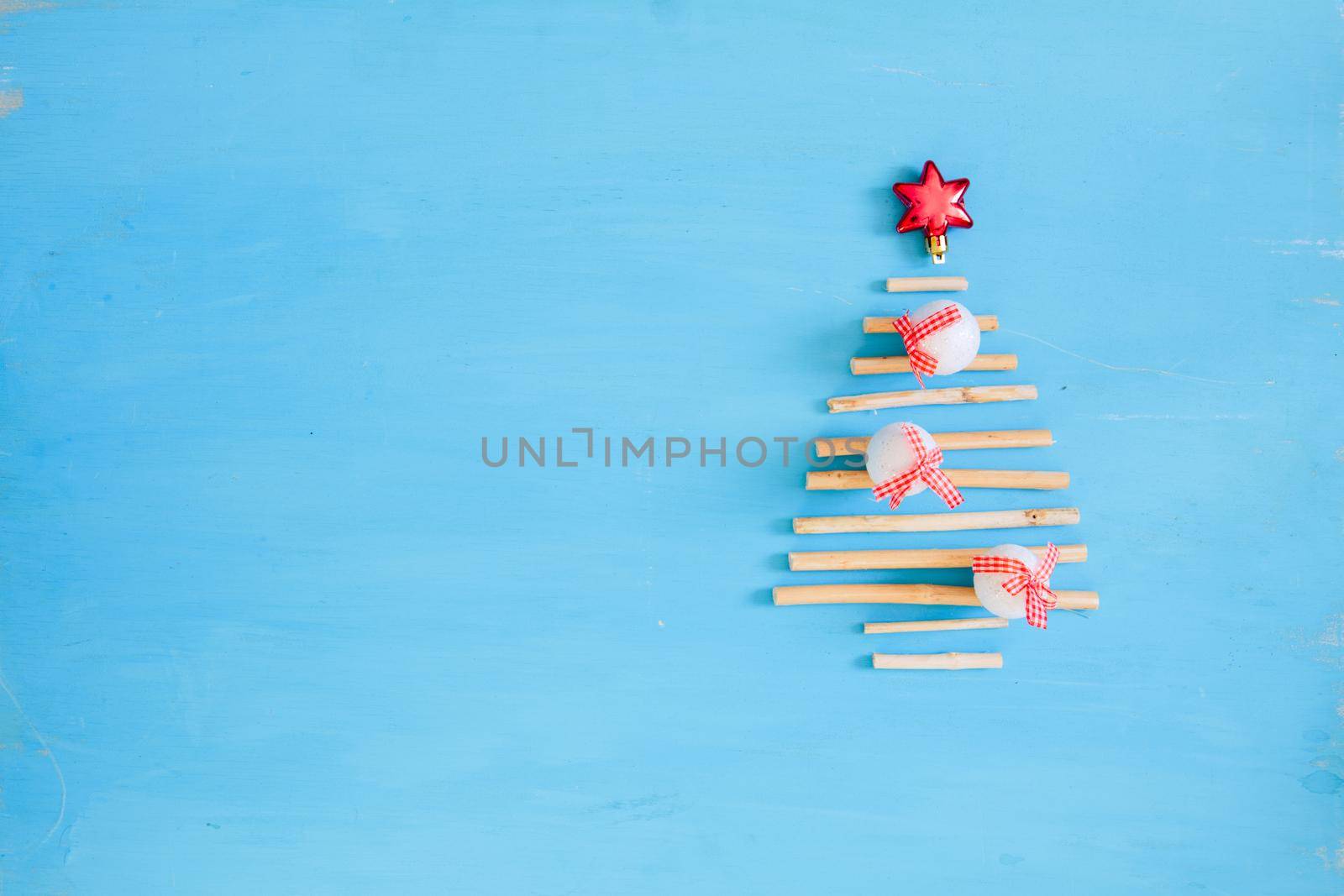 Christmas background. Blue wooden plank with red christmas decorations and xmas tree from dry sticks .