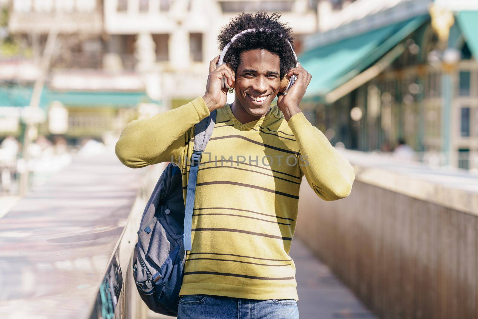 Black man listening to music with wireless headphones sightseeing in Granada by javiindy