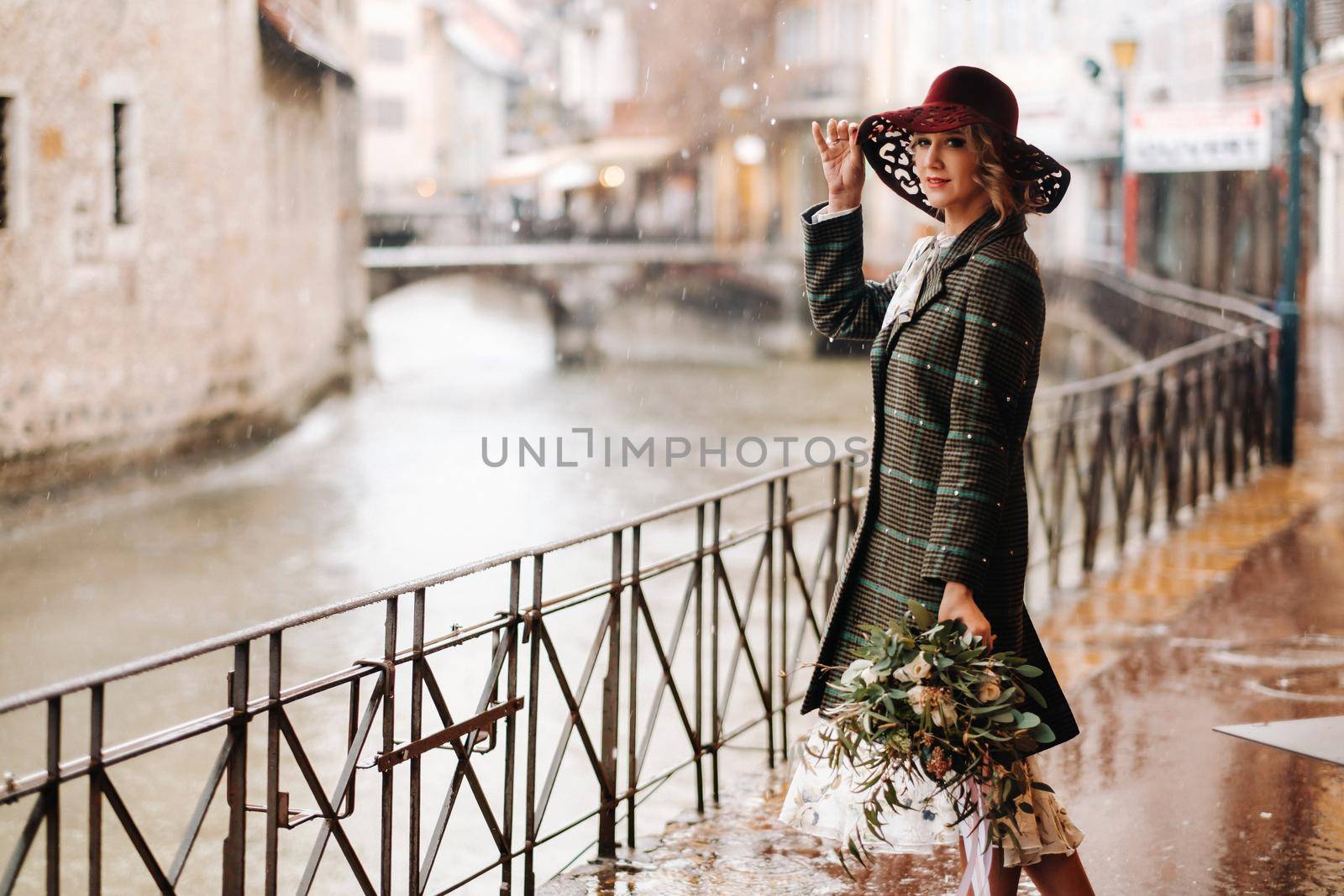 A girl in a hat in rainy weather in the old town of Annecy. France.A woman's walk around the city in rainy weather.