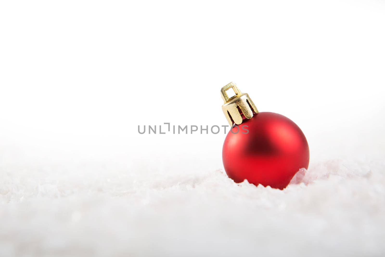 Red christmas ball on snow over white background .