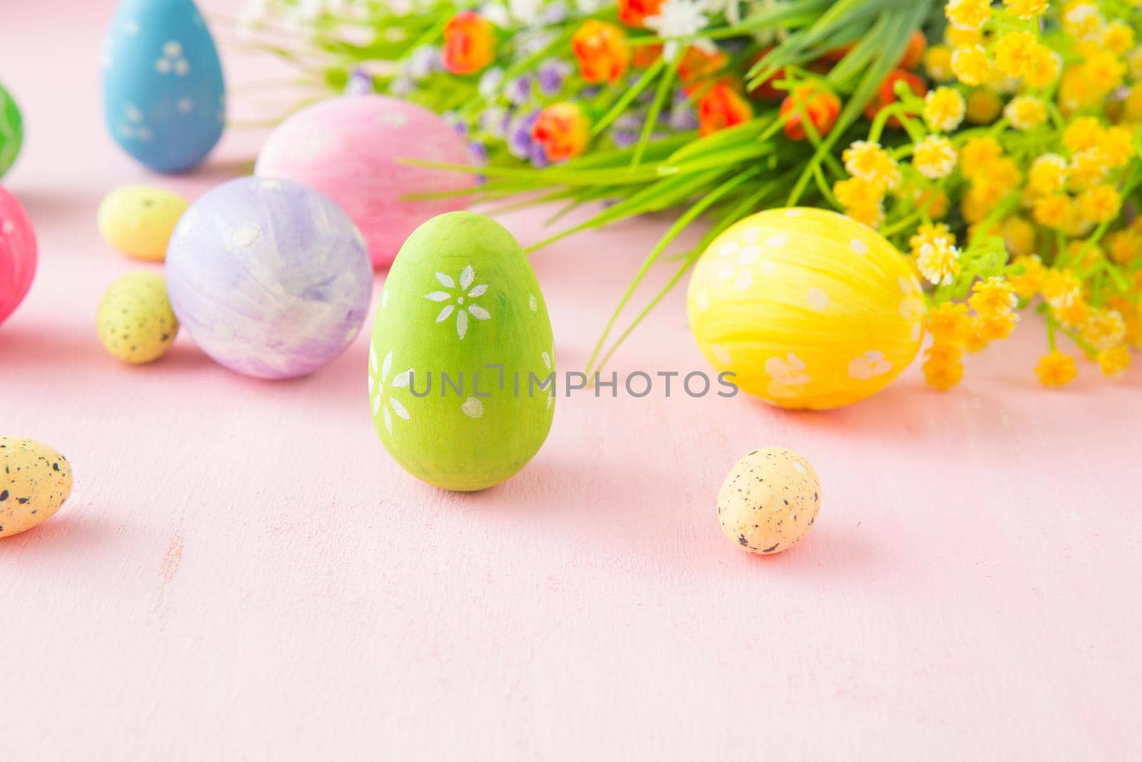 Easter eggs with wild flowers on a wooden pink table background .