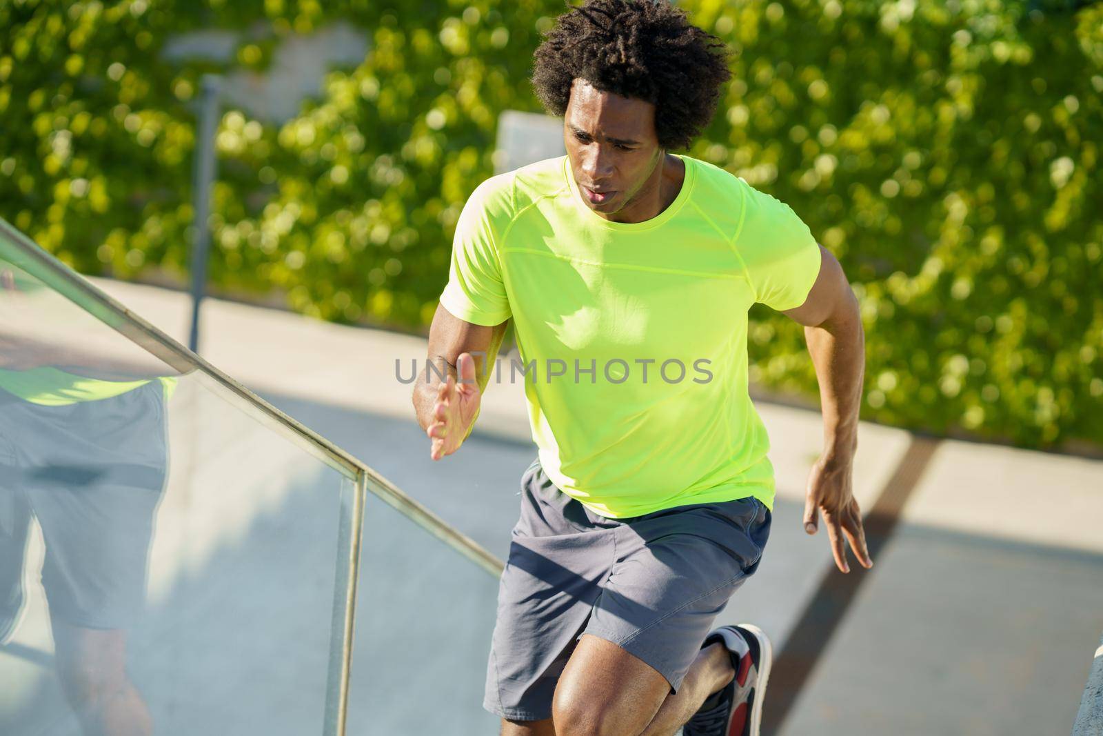 Black man running upstairs outdoors. Young male exercising. by javiindy