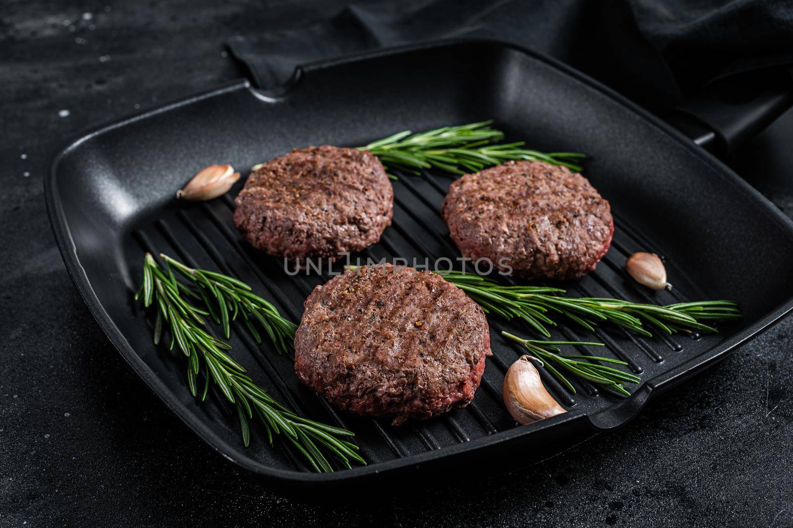 Grilled burger meat patties with spices on grill pan. Black background. Top view by Composter