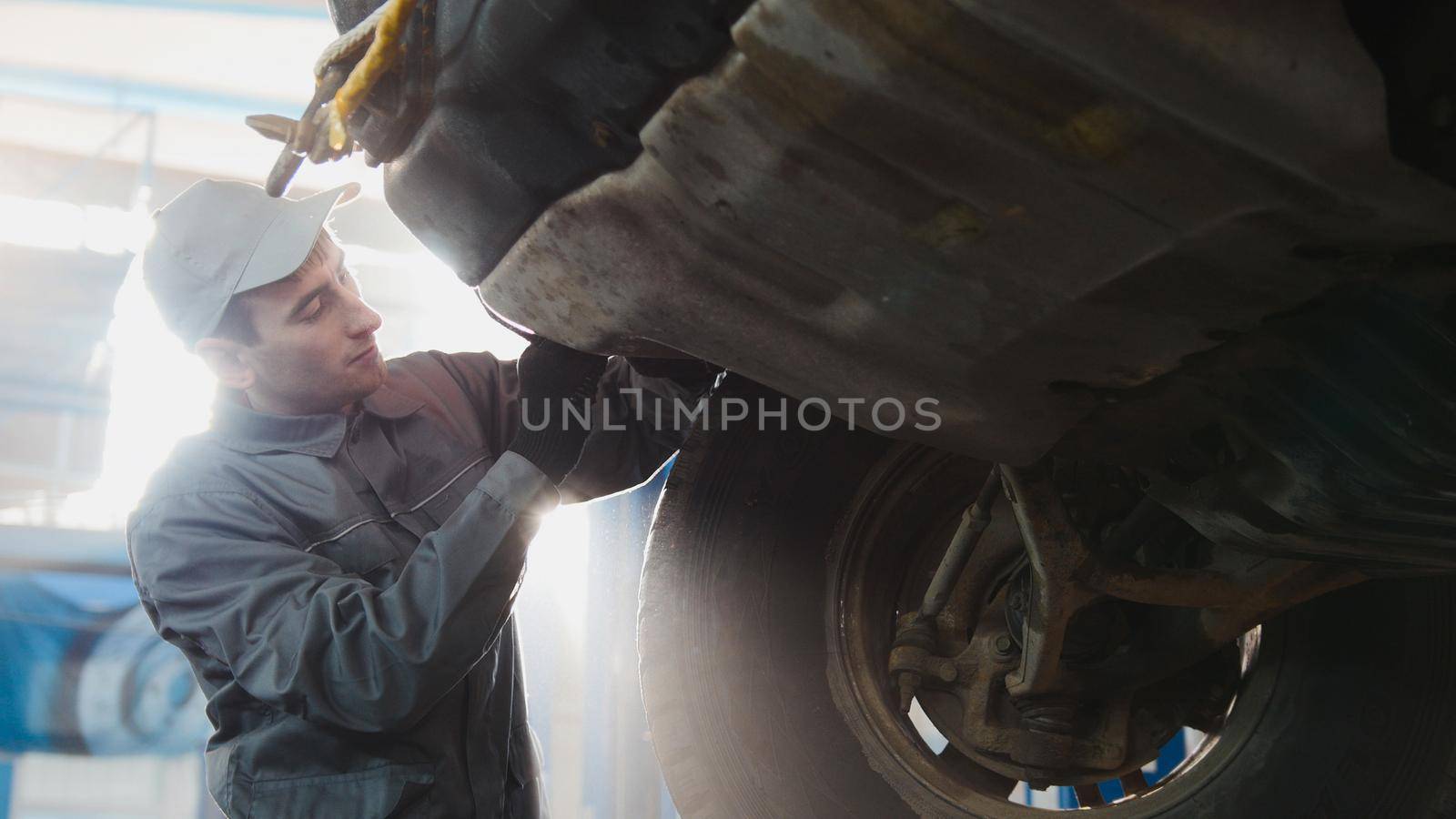 Car service - a mechanic checks the wheel of SUV, wide angle, backlight, horizontal