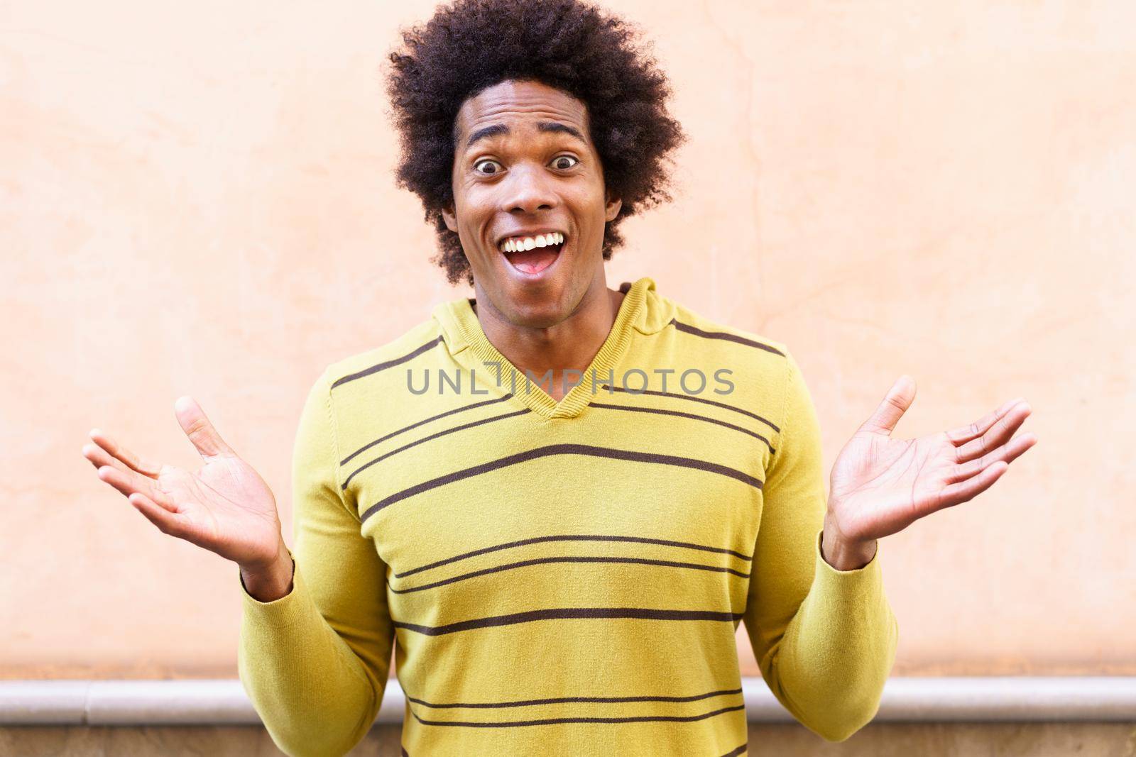 Black man with afro hair putting a funny expression outdoors