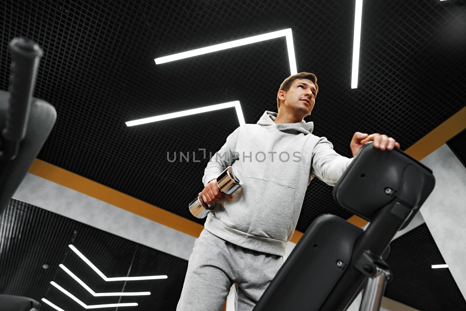 Determined handsome young male working out in gym with dumbbells, close up
