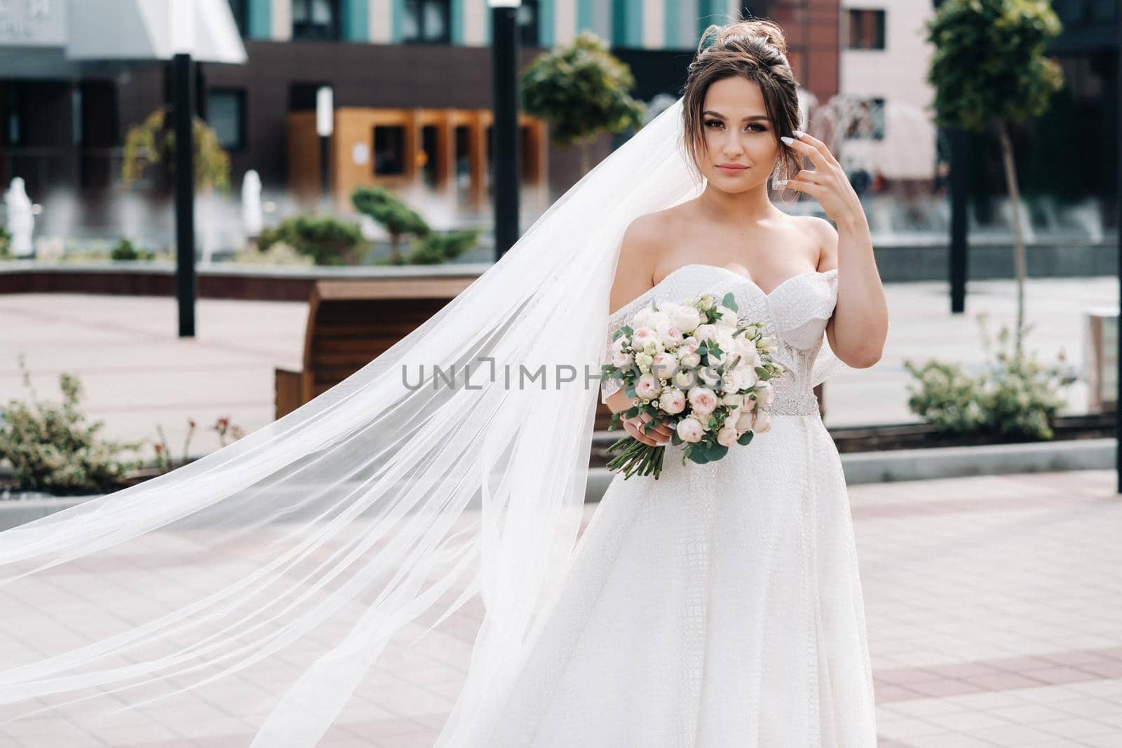 Portrait of the bride in the city near the fountain.A stunning young bride with curly hair . Wedding day. . Beautiful portrait of the bride without the groom. by Lobachad