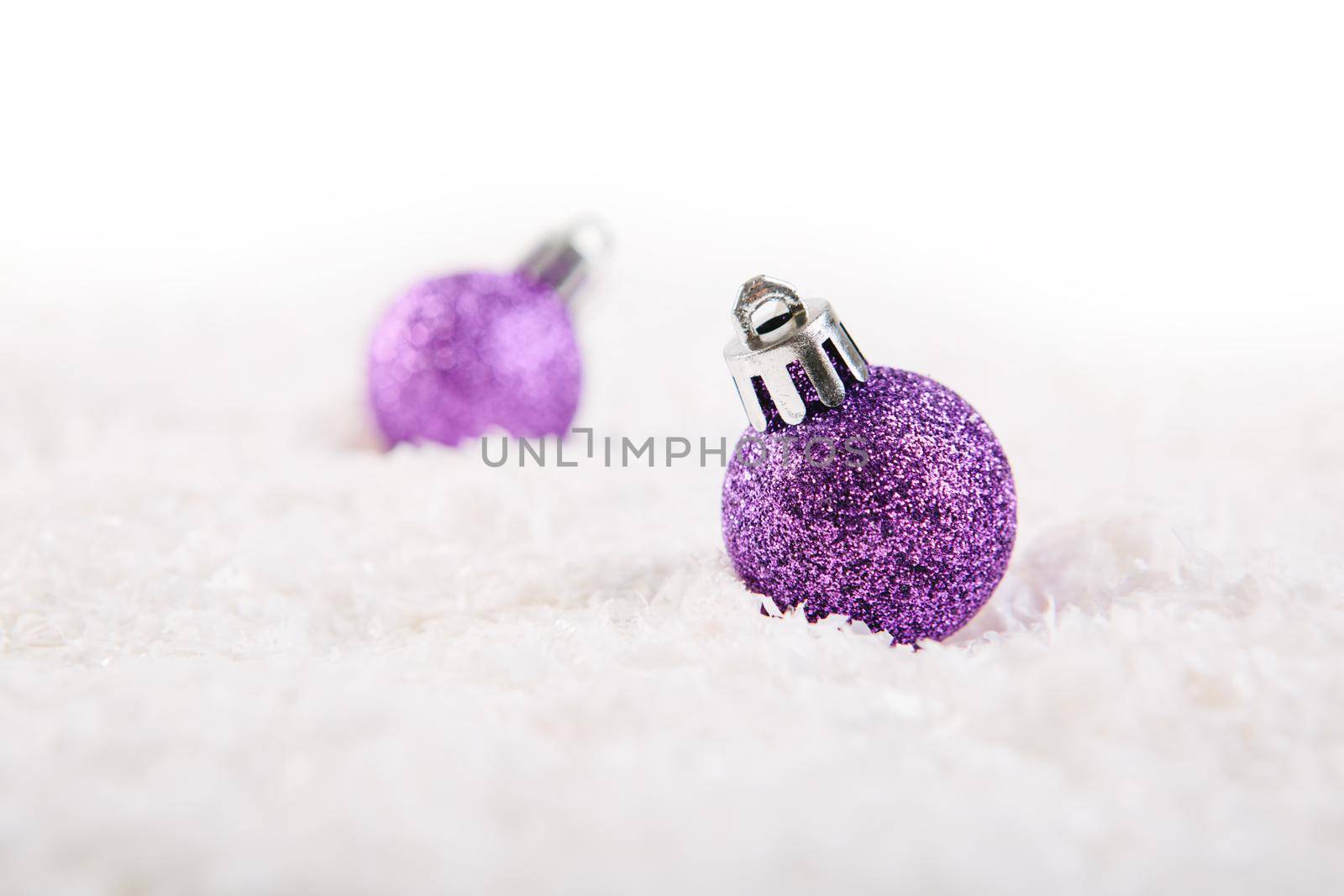 Two Lilac or purple christmas ball on snow over white background .