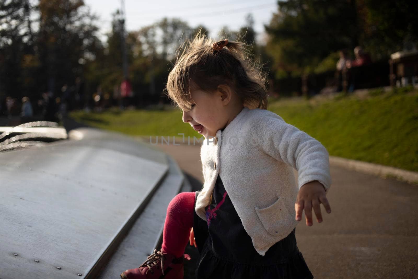 adorable toddler climbs the fountain in the park. weekend walk with children in park in good weather