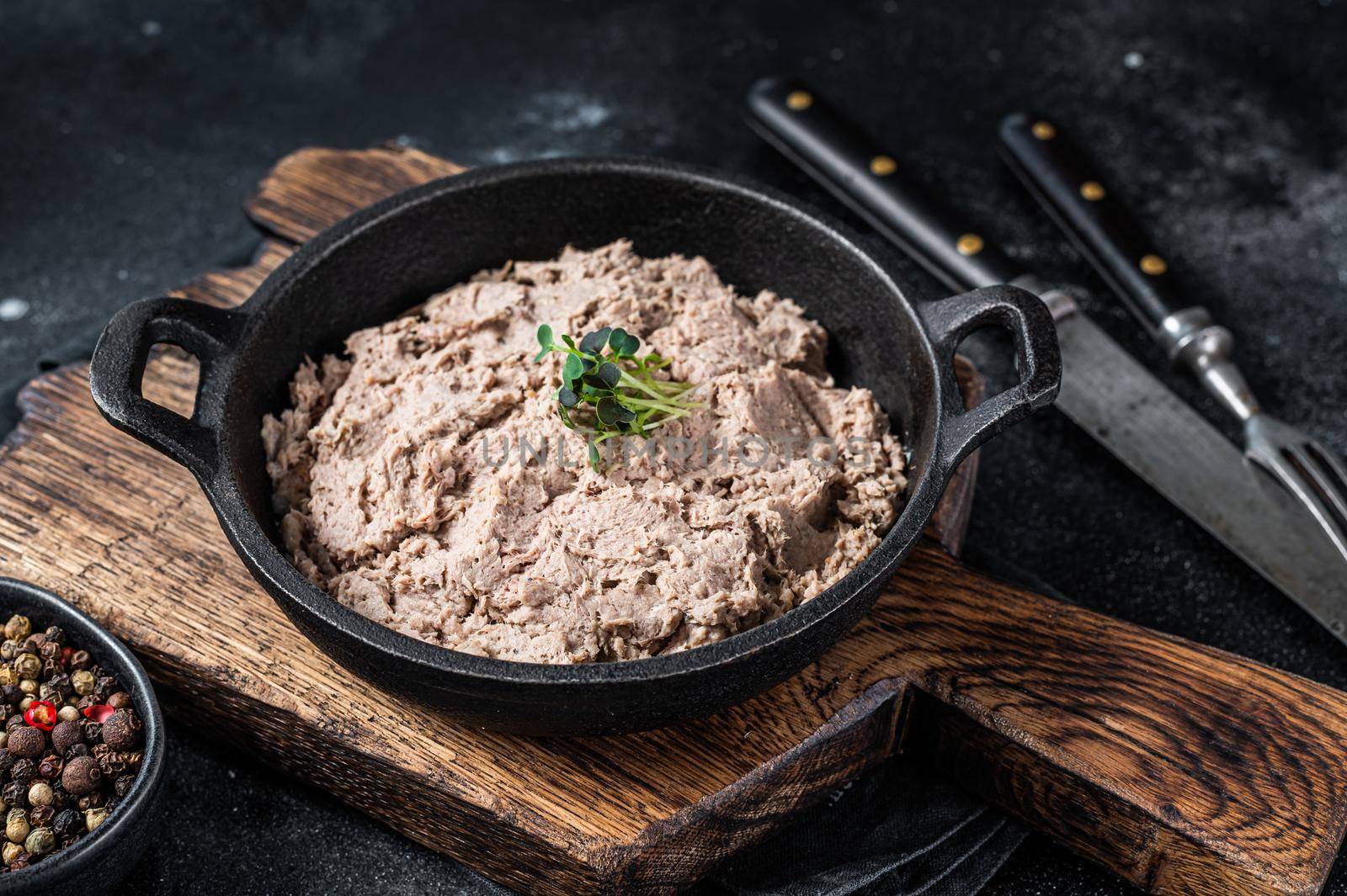 Duck pate Rillettes de Canard in a pan with greens. Black background. Top View.