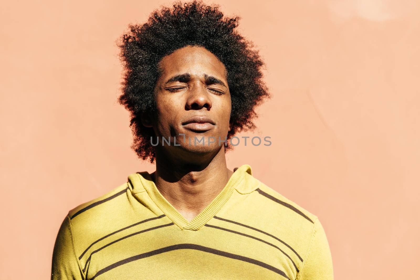 Cuban black man enjoying the andalusian sun with his eyes closed by javiindy