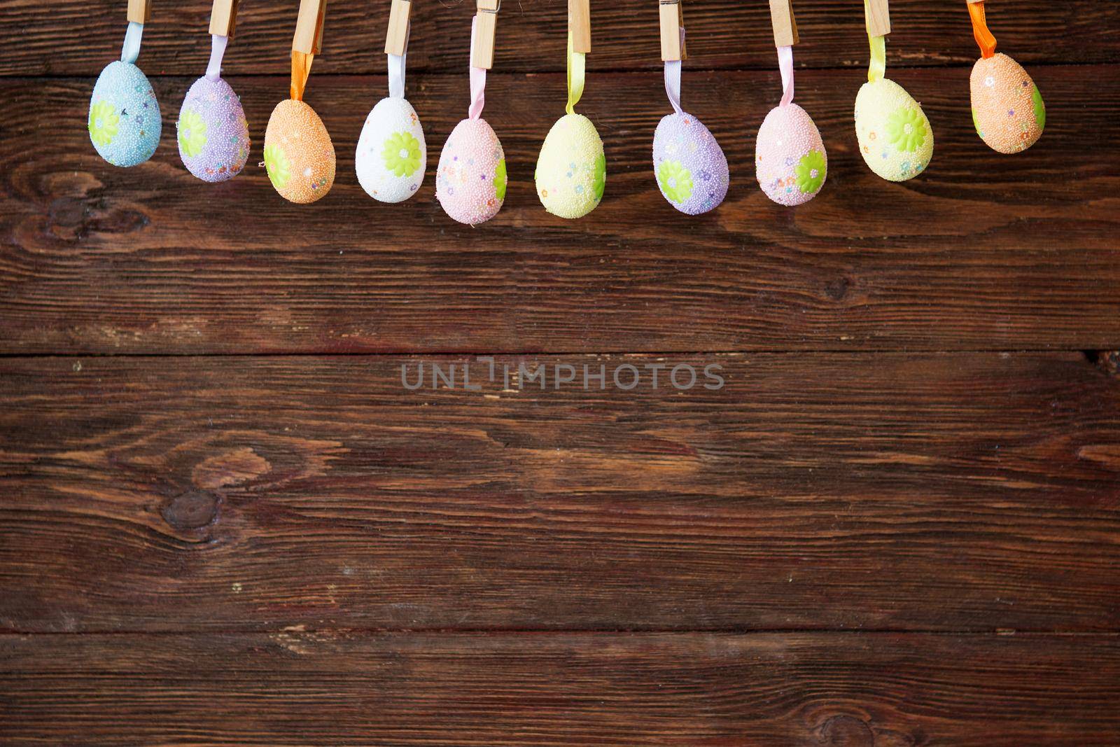 Easter eggs hanging on string over a brown rustic wooden wall. .