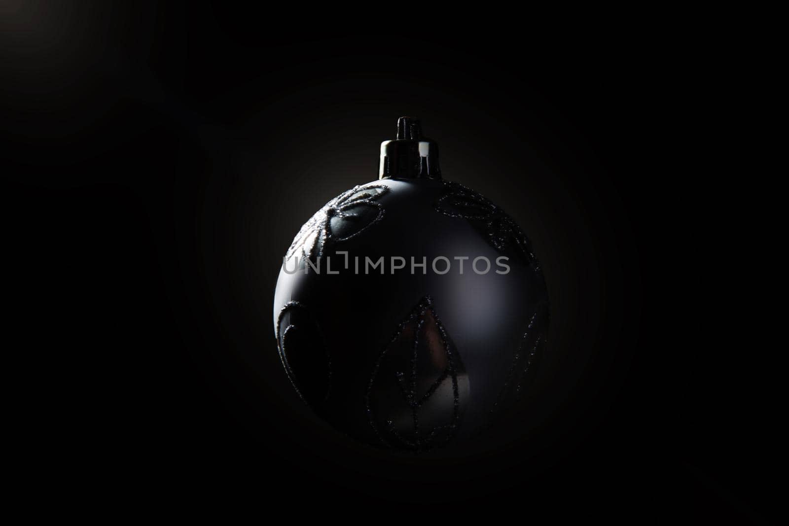 Silver Christmas bauble over dark background. Low key photo. Ball shape. .