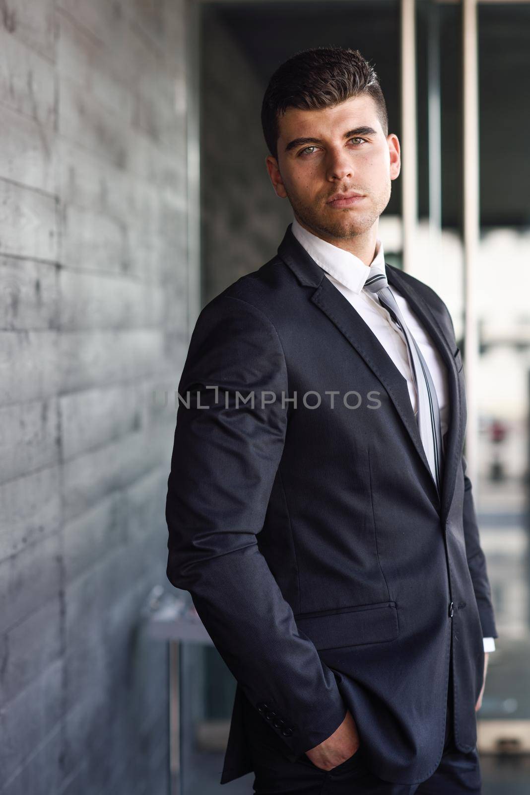 Young businessman near a office building wearing black suit by javiindy