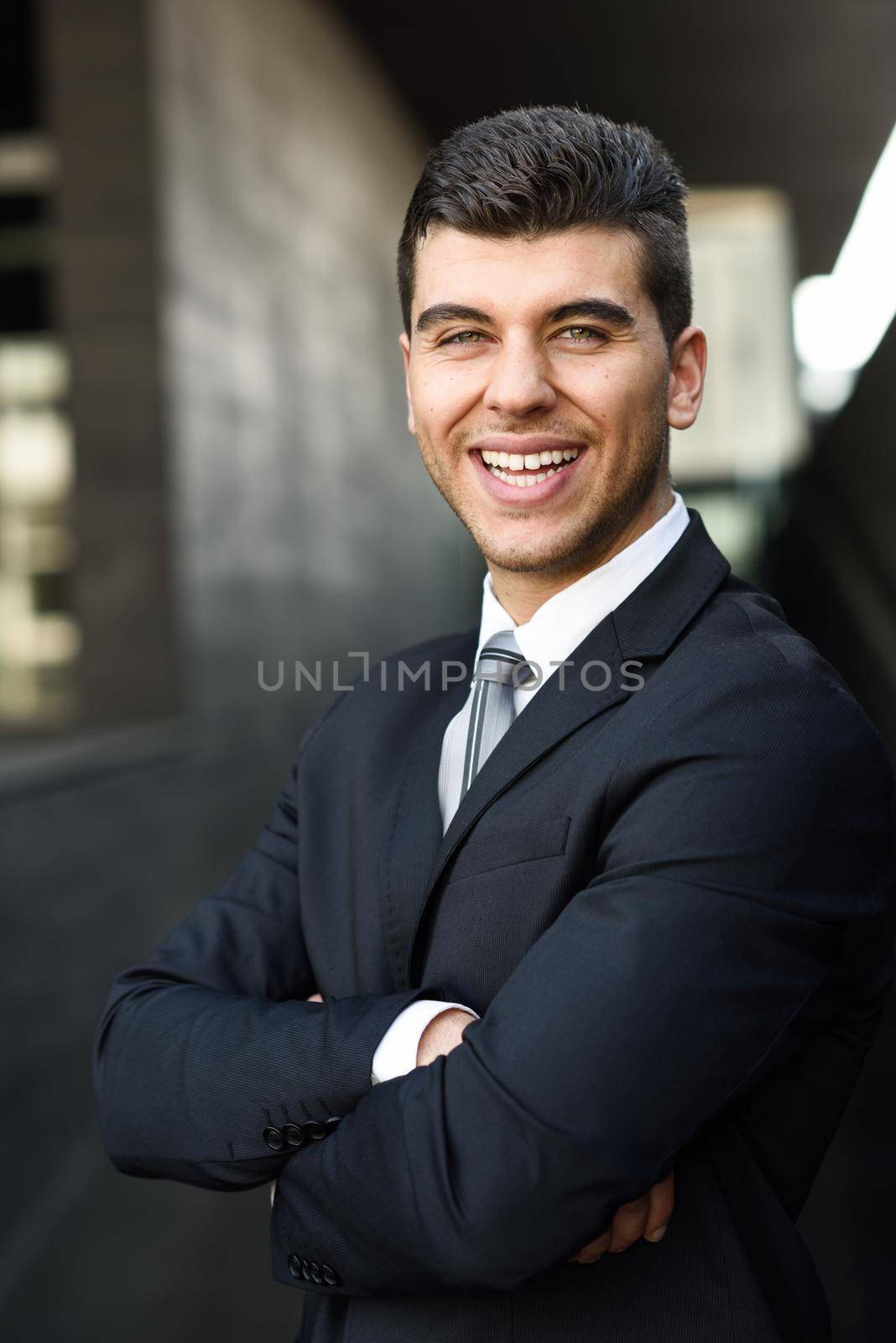 Young businessman near a office building wearing black suit by javiindy