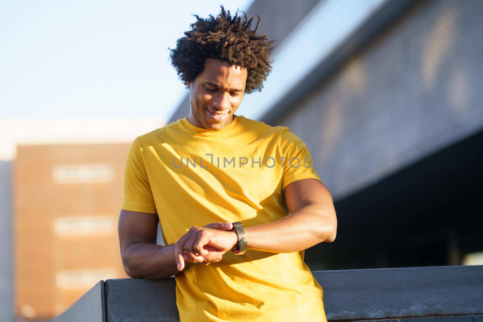 Black man with afro hair consulting his smartwatch to view his training data.