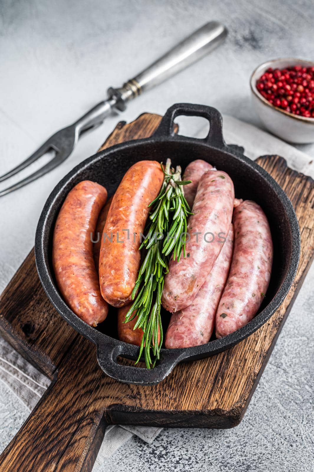 Assorted Raw sausages Chorizo and Bratwurst with spices in a pan with rosemary. White background. Top View by Composter