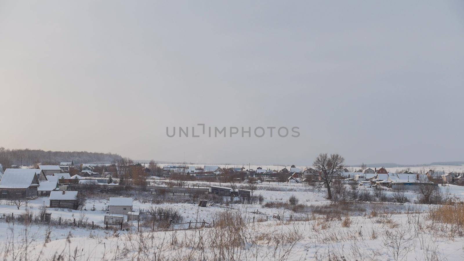 View of typical Russian village at winter - cold day in snow-covered field, wide angle
