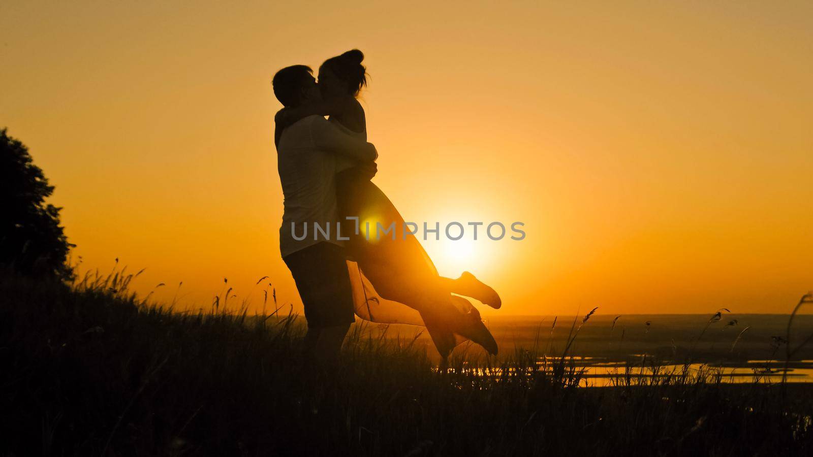 Romantic Silhouette of Man Getting Down on his Knee and Proposing to Woman on high hill - Couple Gets Engaged at Sunset - Man Putting Ring on Girl's Finger, telephoto