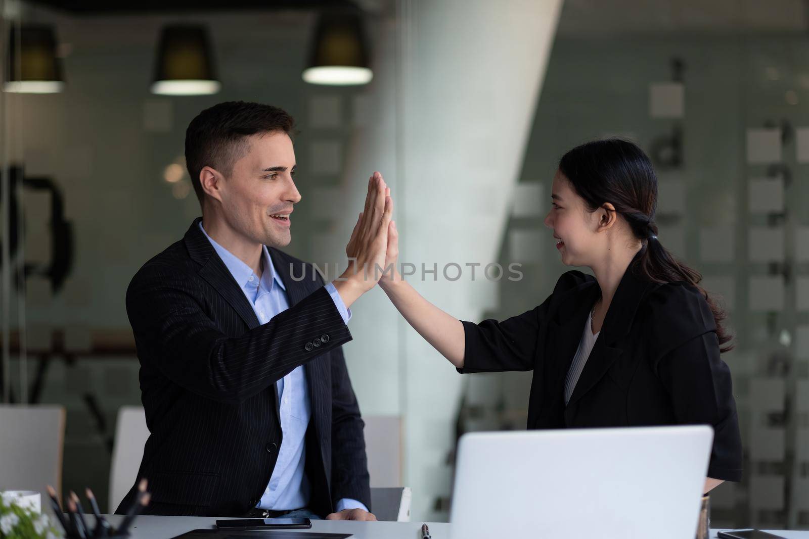 Business man and woman business hi five bump hand together for team work, diversity business team concept. by nateemee