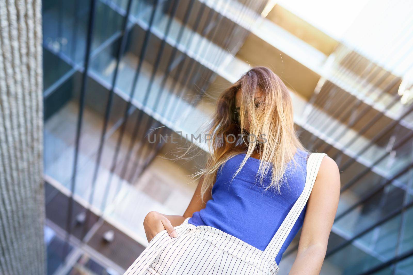View from below of young girl moving her hair wild outdoors