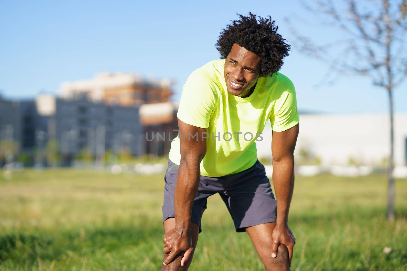 Black man with afro hair exhausted after exercising. Man taking a break after hard workout.