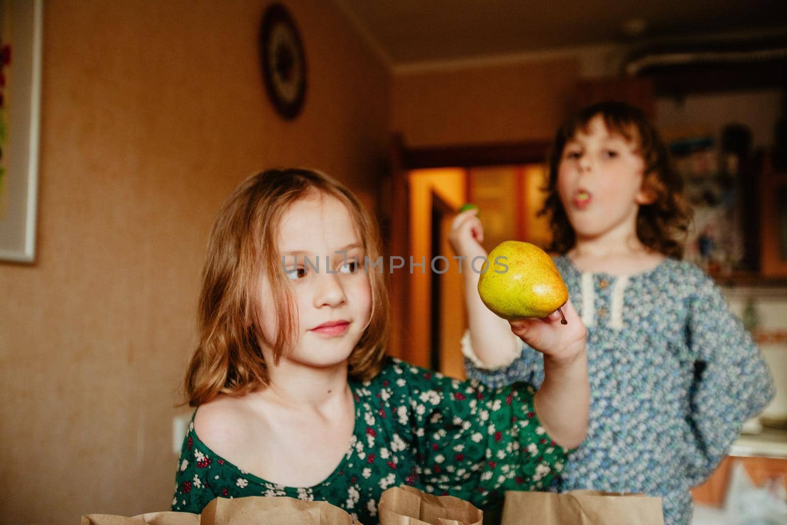 Cute child with ripe green pear in kitchen showing concept of healthy food
