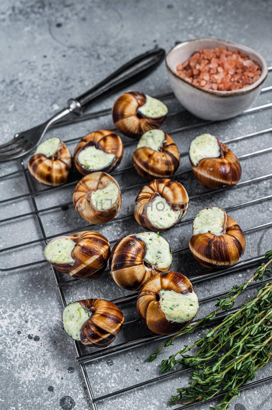 Bourgogne Escargot Snails with garlic butter on a grill. Gray background. Top view.