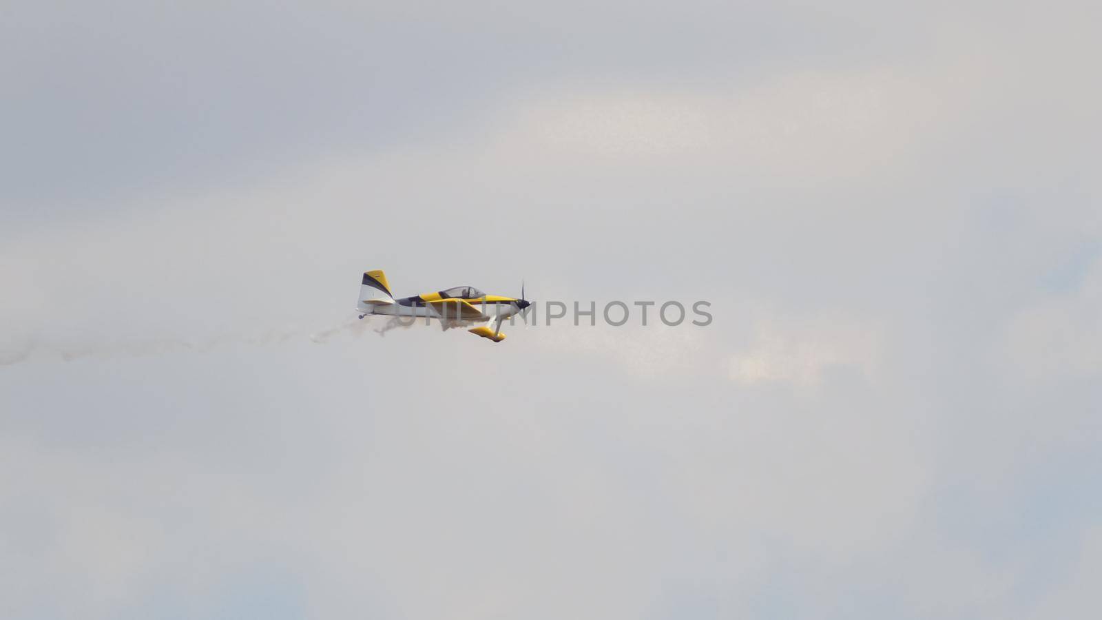 Small yellow Airplane flying in an extreme acrobatics exhibition, telephoto