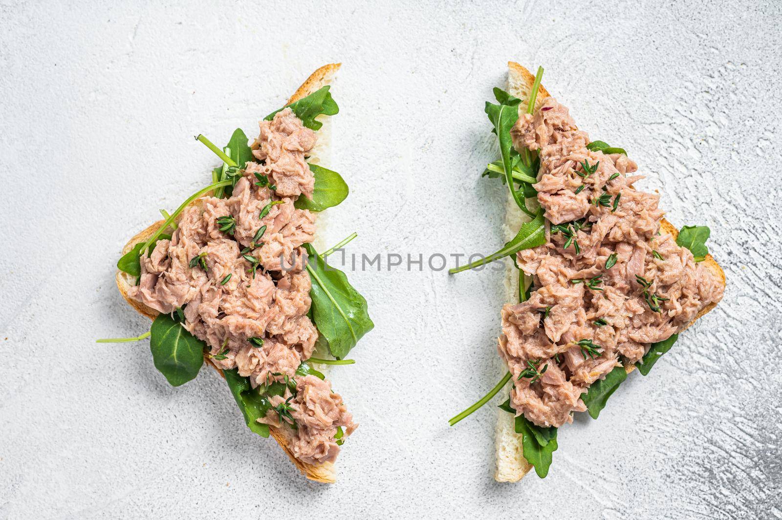 Toast with Canned Tuna fish and arugula. White background. Top view by Composter