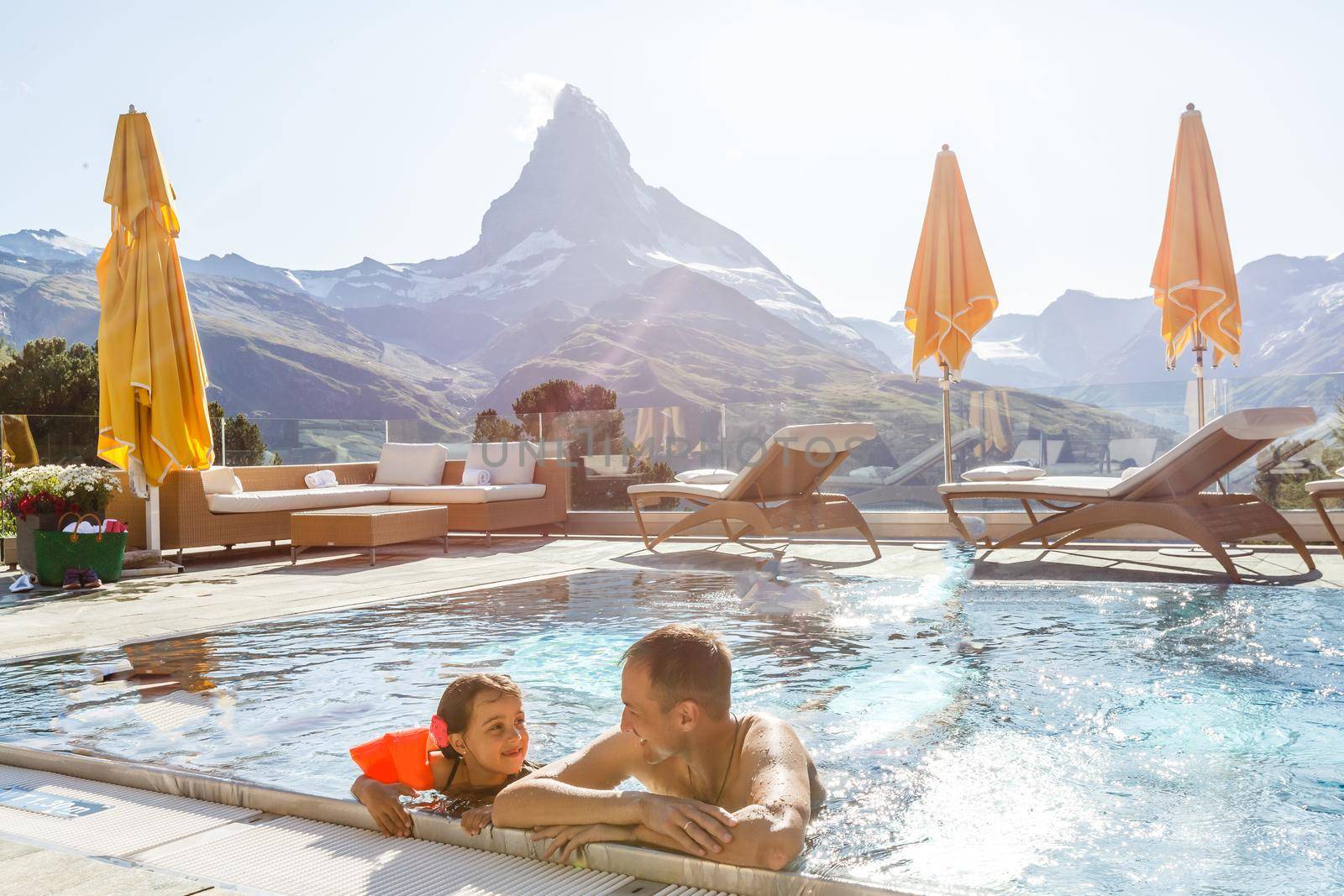 Family In Swimming Pool In Mountains. Beautiful outdoor scene in Swiss Alps, Switzerland, Europe. by Andelov13