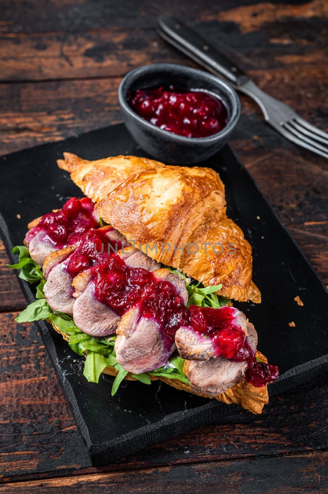 Sandwich with Duck breast fillet steak slices, arugula and sauce. Dark wooden background. Top View.