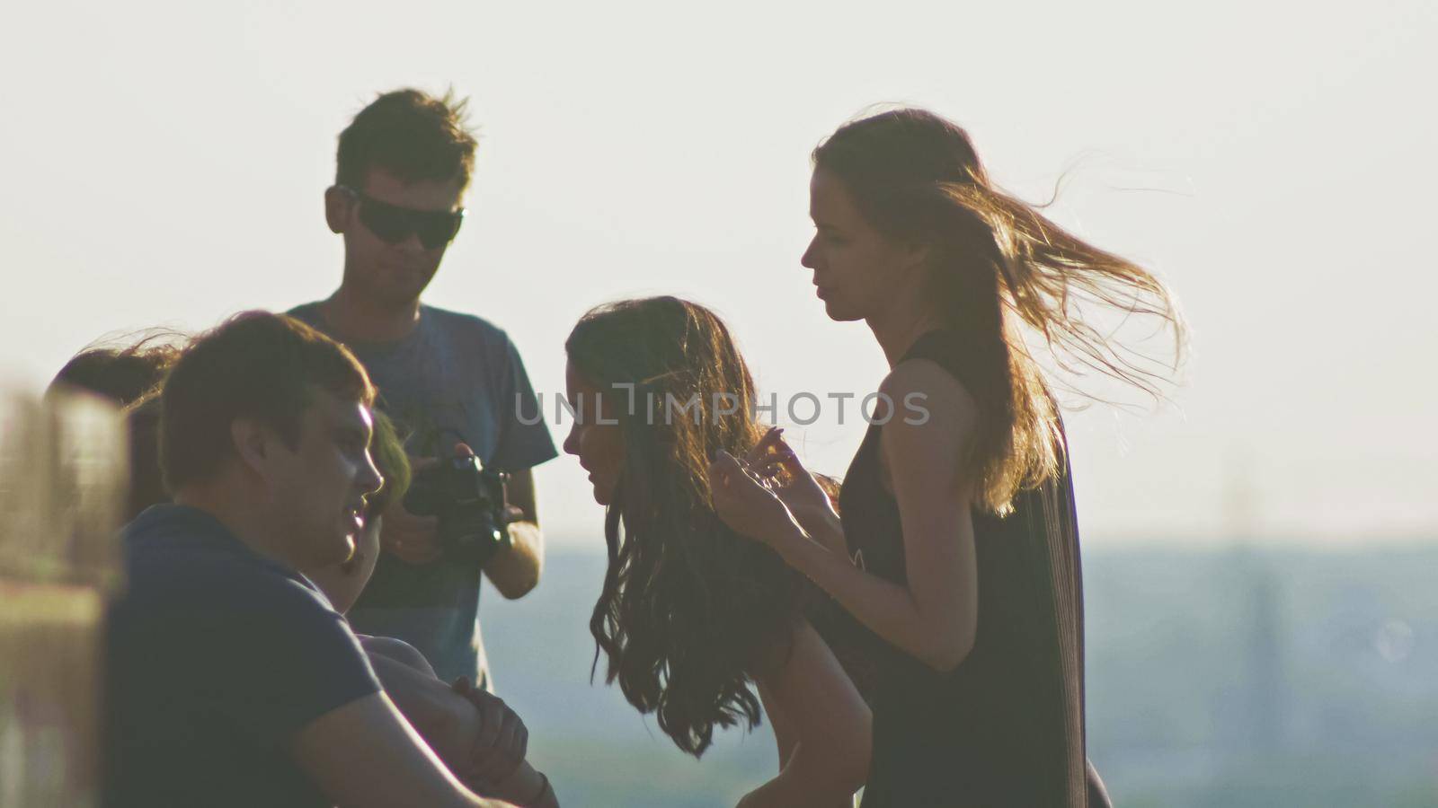 Happy young attractive group of friends having fun and looks at wedding dress together outdoors on a summer day slow-motion