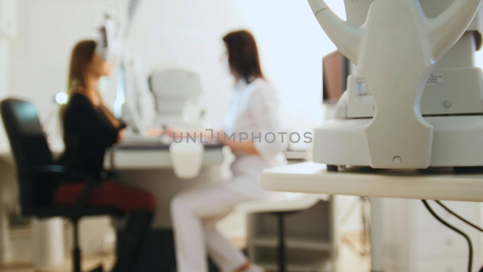 Eye diagnostic clinic concept - optician with tonometer and patient, blurred by Studia72