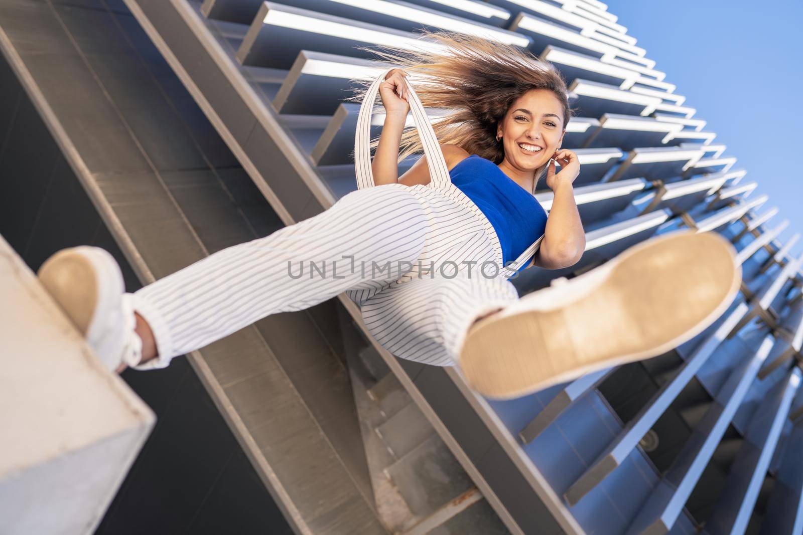 View from below of young girl throwing her foot in the air. by javiindy
