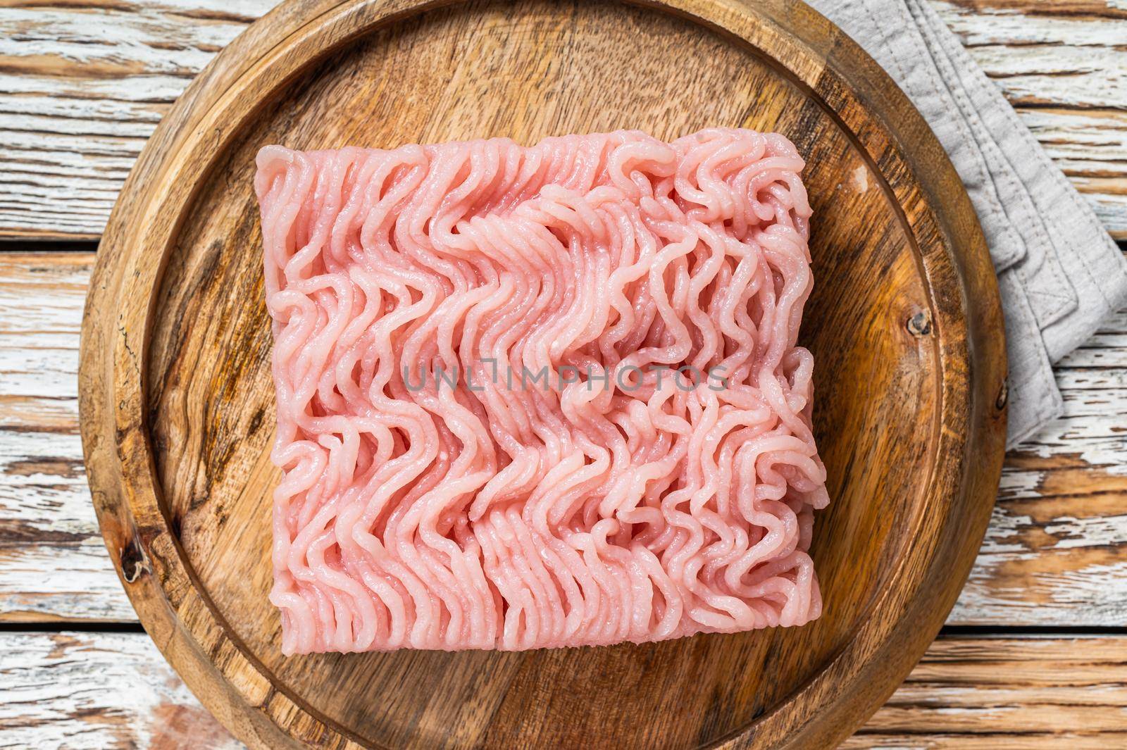 Raw mince or ground chicken meat on wooden board. White background. Top view.