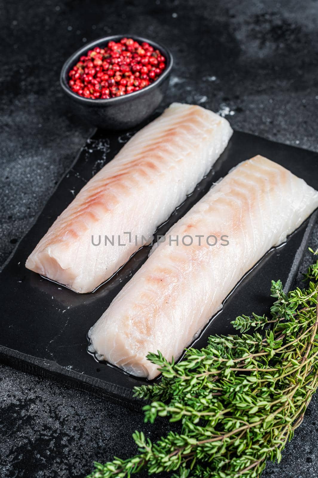 Raw cod loin fillet fish on marble board. Black background. Top view by Composter