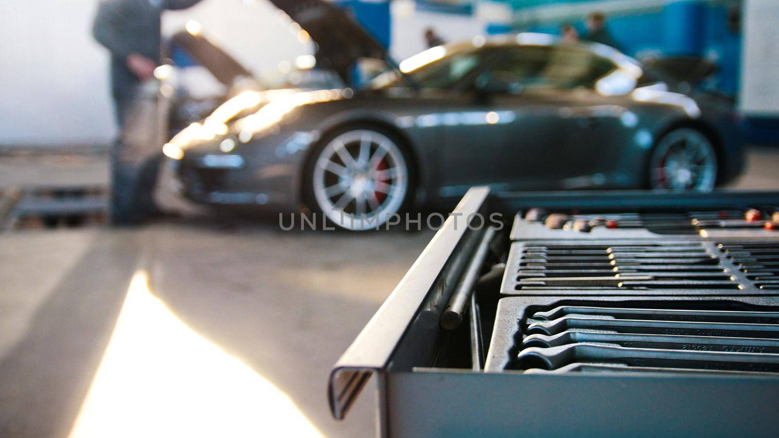 A set of tools for repair in car service in front of luxury sport car, wide angle