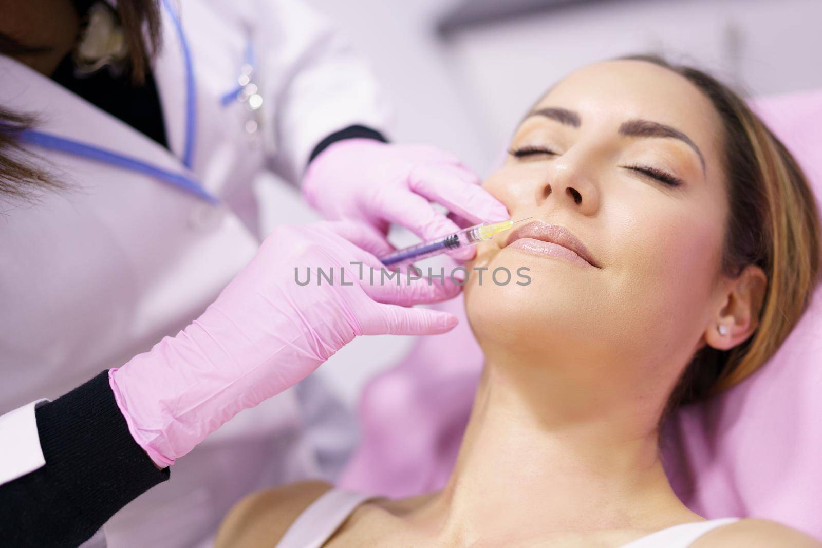 Doctor injecting hyaluronic acid in the face of a woman as a facial rejuvenation treatment. by javiindy