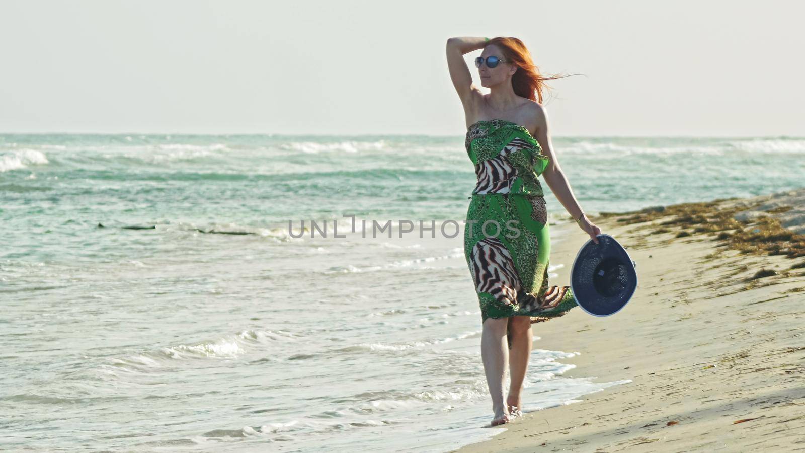 Young woman with long red hair walking at seascape beach in Dominican Republic, Caribbean sea