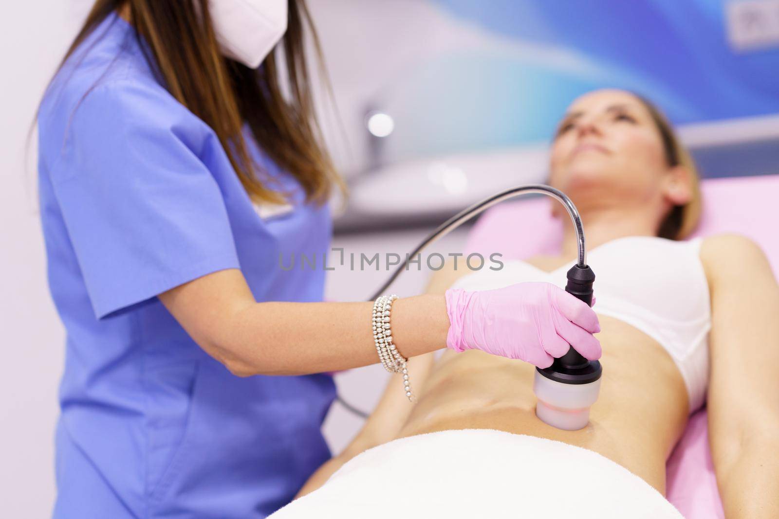 Middle-aged woman receiving anti-cellulite treatment with radiofrequency machine in a beauty center.
