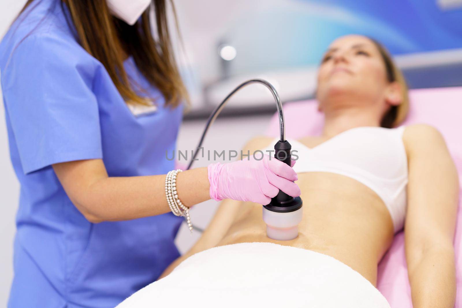 Middle-aged woman receiving anti-cellulite treatment with radiofrequency machine in an aesthetic clinic.