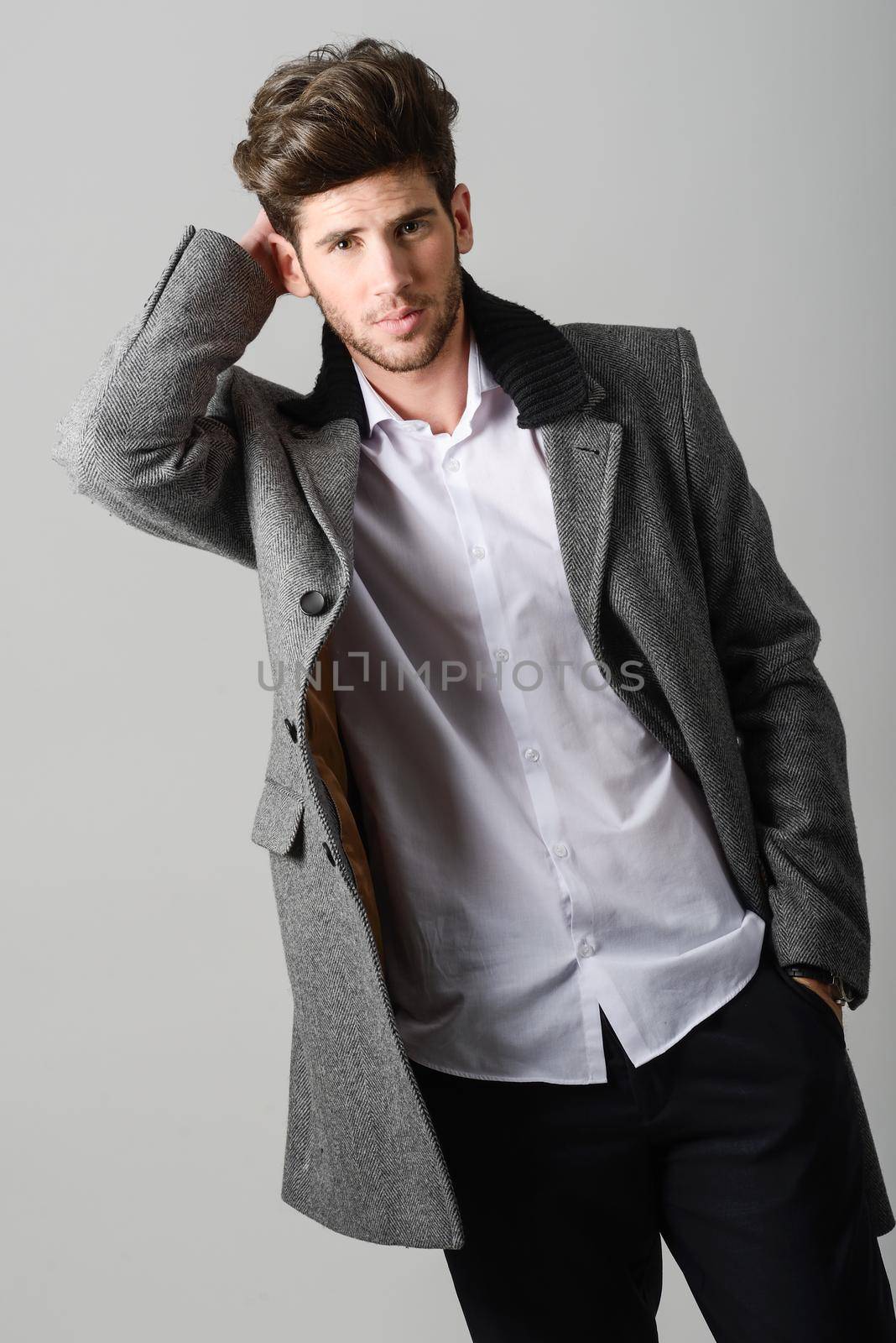 Portrait of handsome man, model of fashion, wearing coat. Studio shot