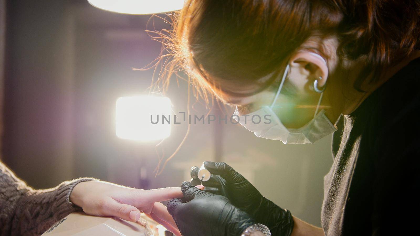 Professional beauty salon - manicure master doing cosmetic procedure for attractive young woman, close up by Studia72