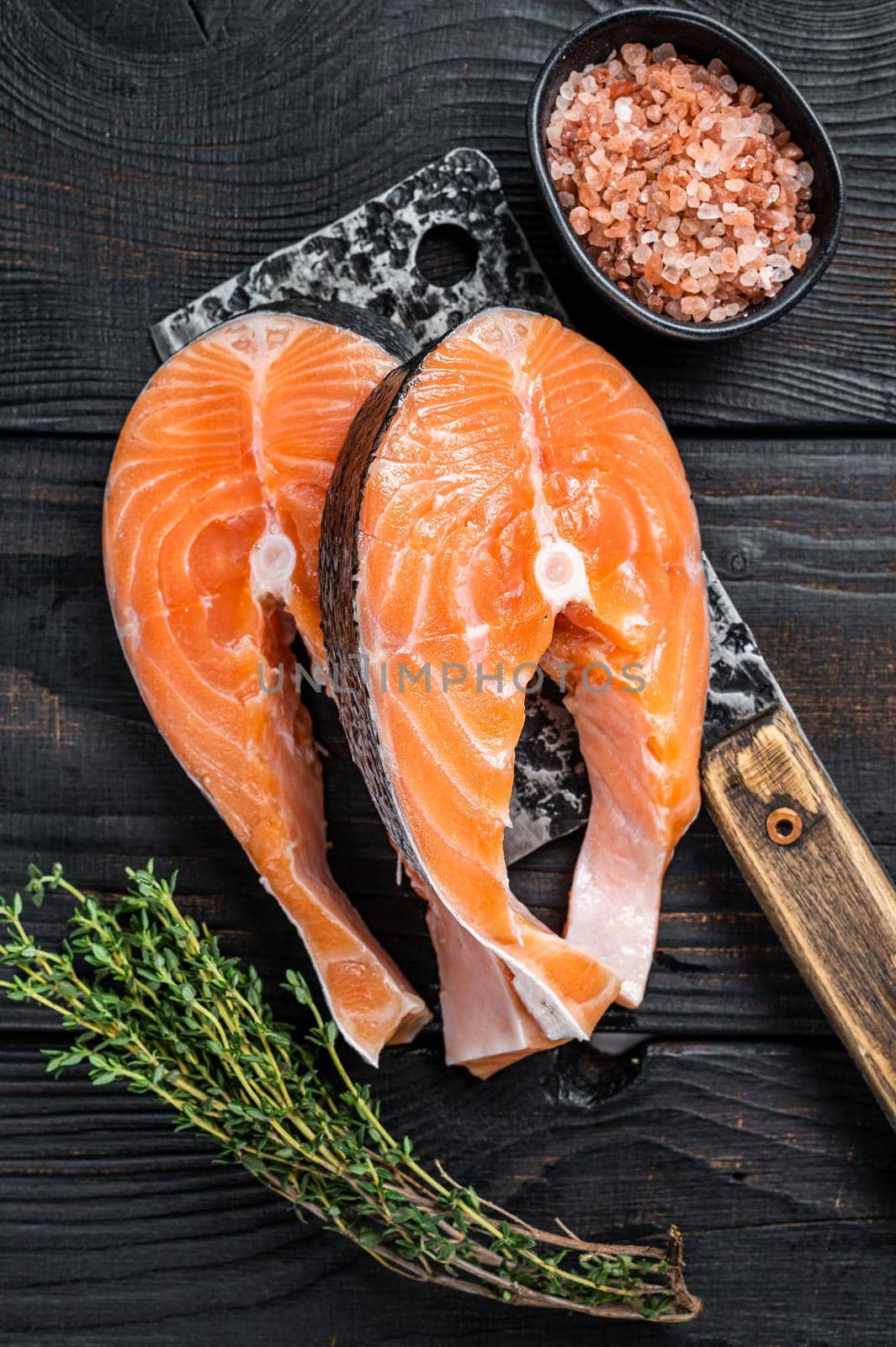 Fresh Raw Salmon steaks on butcher cleaver. Black wooden background. Top view by Composter