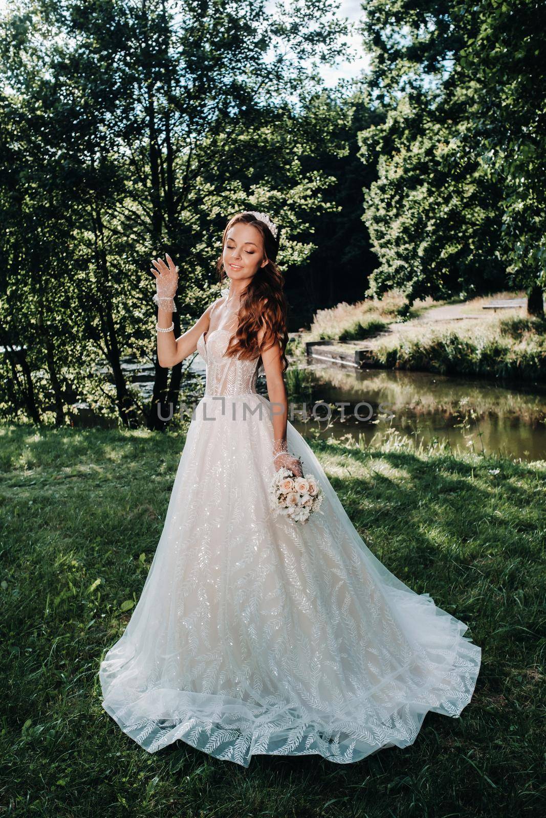 portrait of an elegant bride in a white dress with a bouquet in nature in a nature Park.Model in a wedding dress and gloves and with a bouquet .Belarus by Lobachad