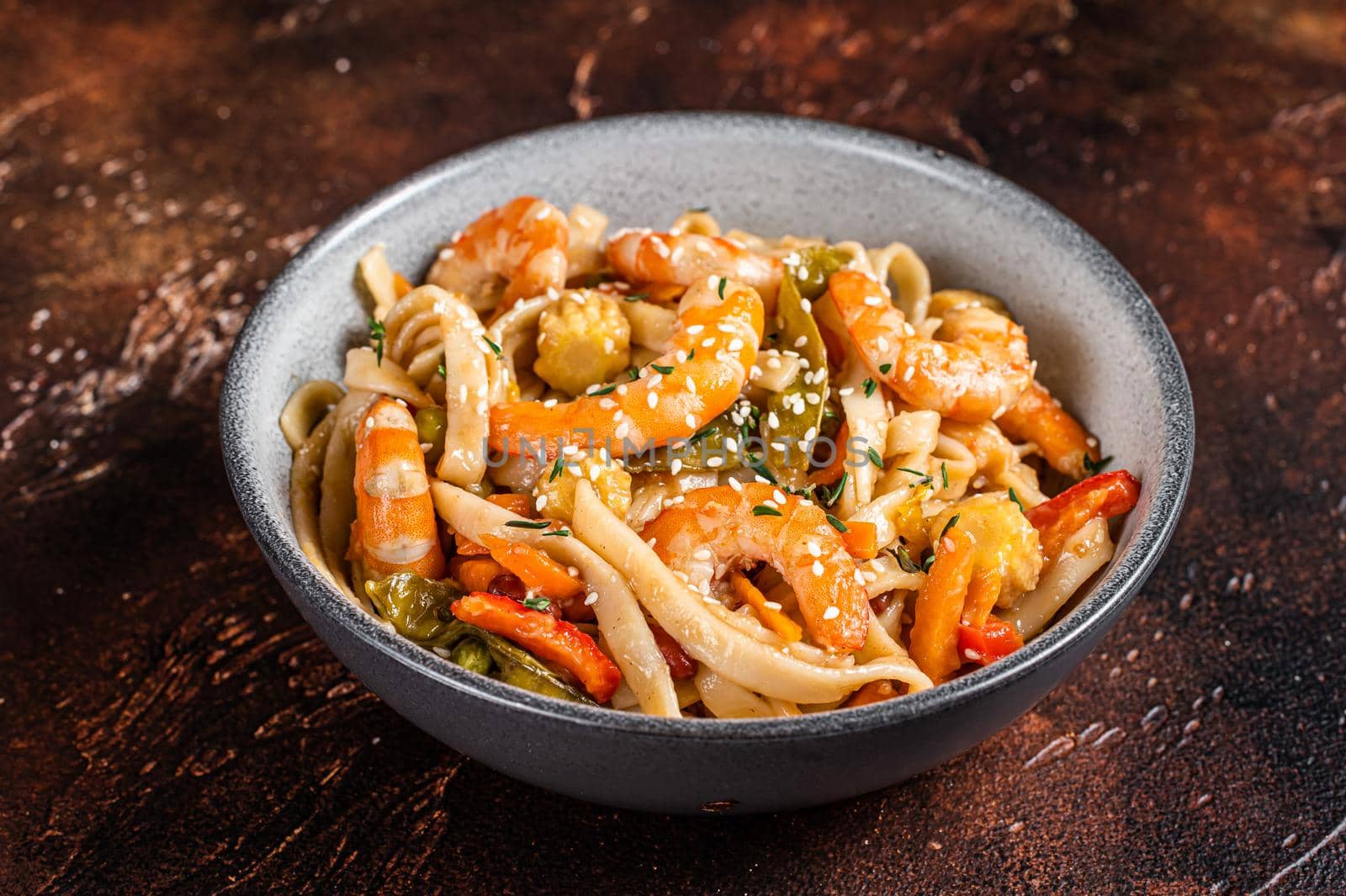 Chinese wok Stir-fry udon seafood noodles with shrimp prawns in a bowl. Black background. Top view by Composter