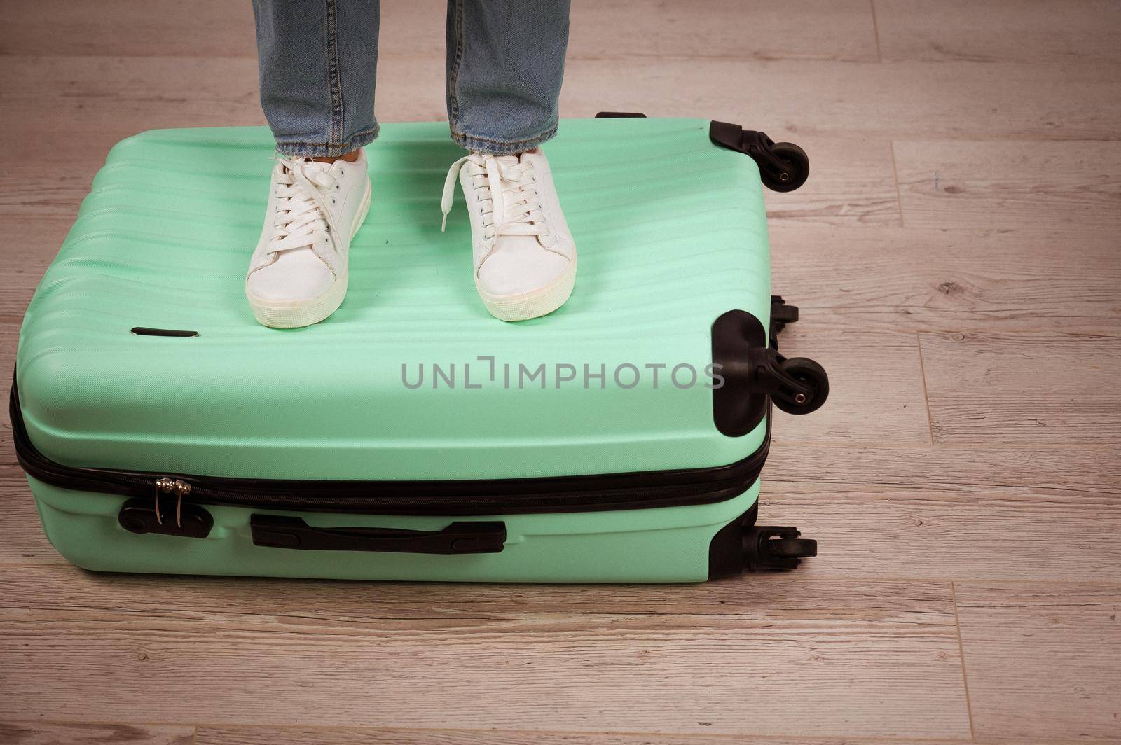 Woman standing with her feet on a suitcase