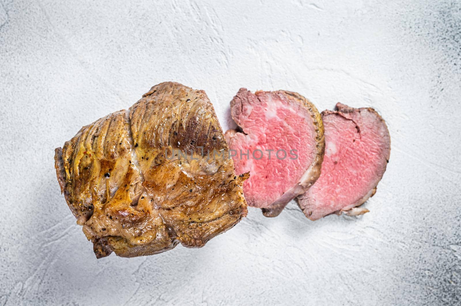 Roast beef meat fillet on kitchen table. White background. Top view by Composter